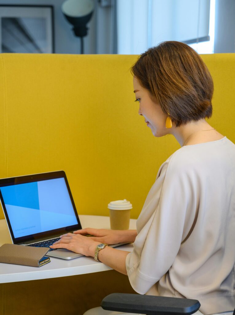 Asian woman focusing on her laptop in a contemporary office environment.