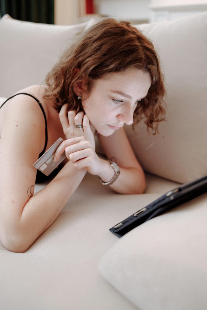 Young woman using a tablet for online shopping at home, holding a credit card.