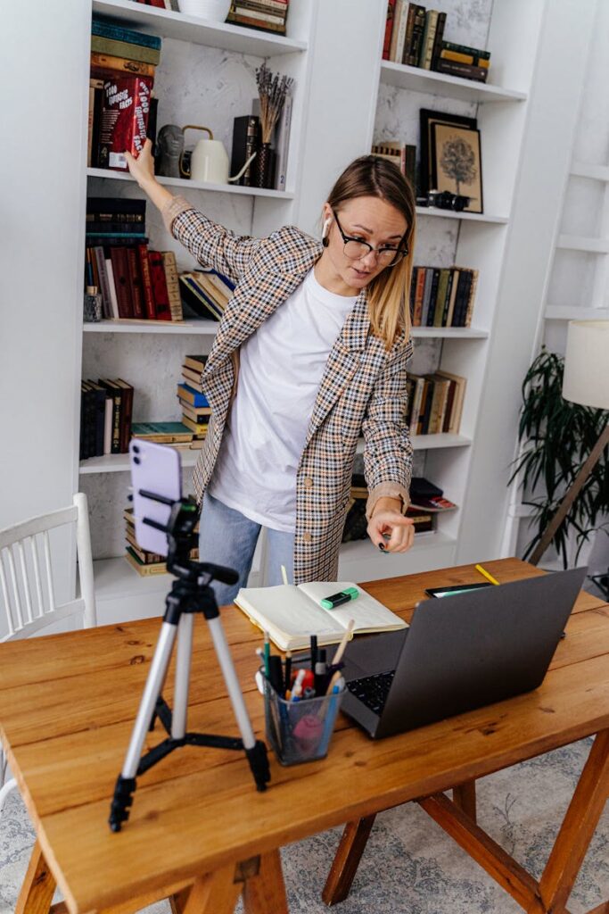 A woman conducting an online class from her home with a laptop and smartphone setup.