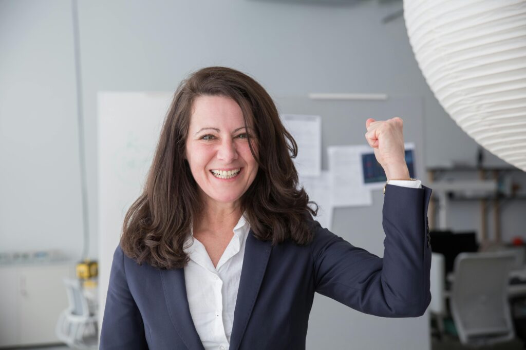 Smiling businesswoman in a smart suit celebrating a success in the office.