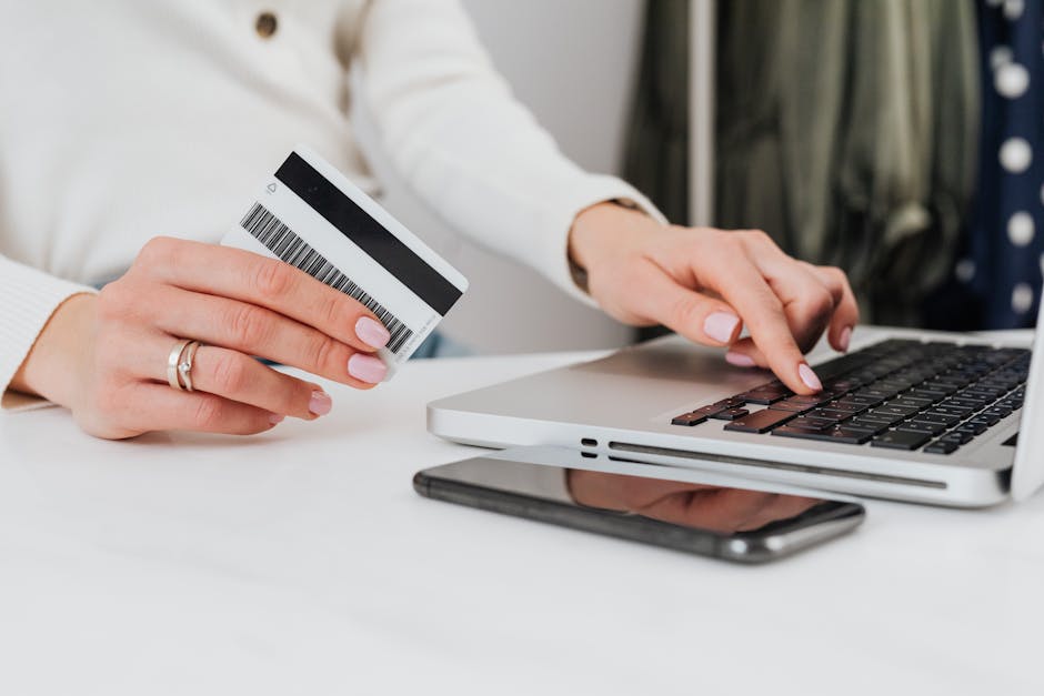 Close-up of a woman using a credit card for an online transaction on a laptop.